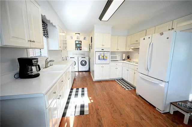 a kitchen with granite countertop a refrigerator stove and white cabinets