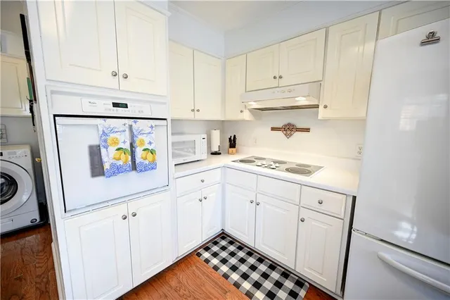 a kitchen with granite countertop white cabinets and white appliances