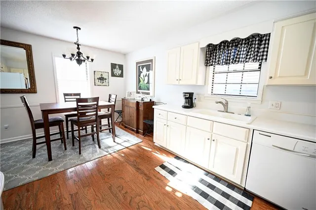 a kitchen with stainless steel appliances granite countertop sink stove and white cabinets with wooden floor