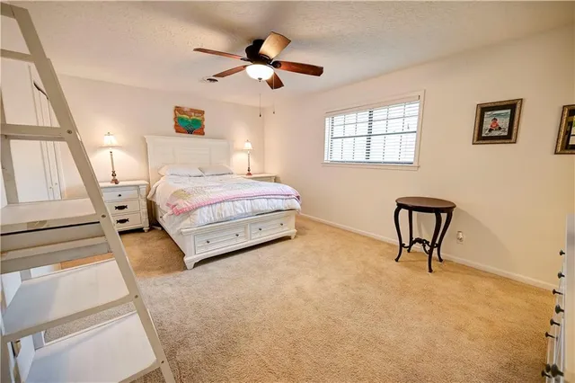 a spacious bedroom with a bed a dresser and a chandelier