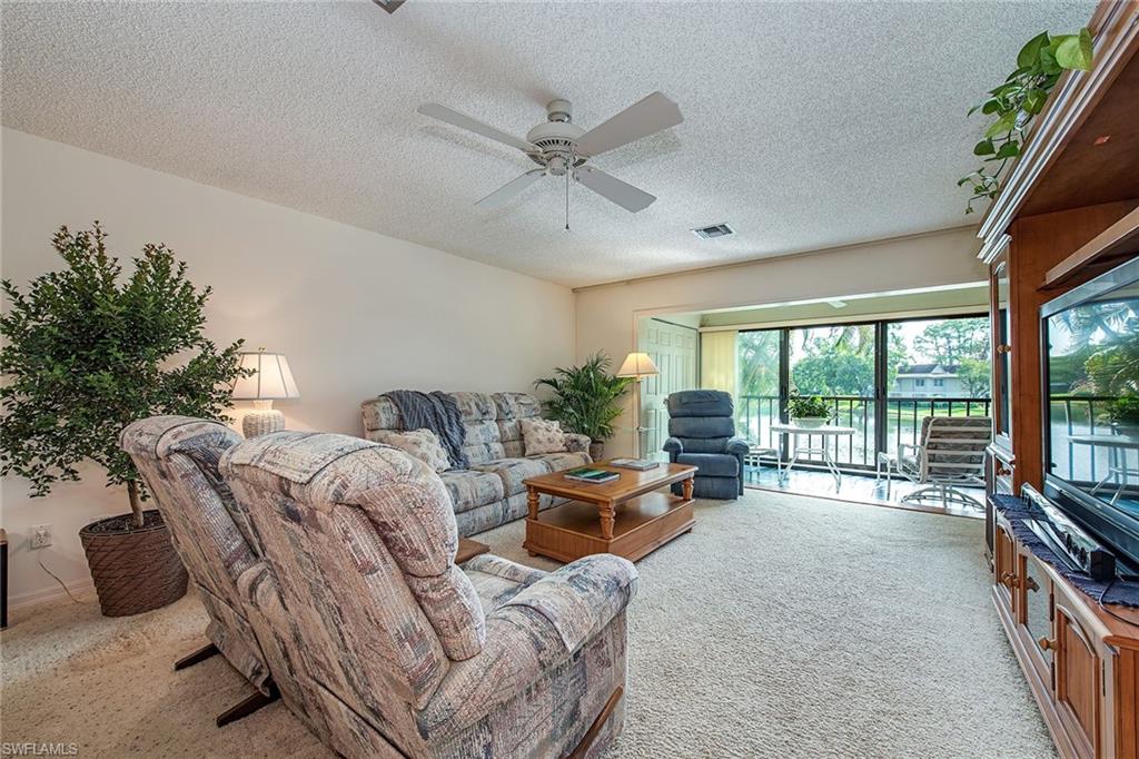 1672 Spoonbill Lane, Unit 1672 Naples, FL 34105 - Photo 2 of 12 a living room with furniture large windows and flat screen tv