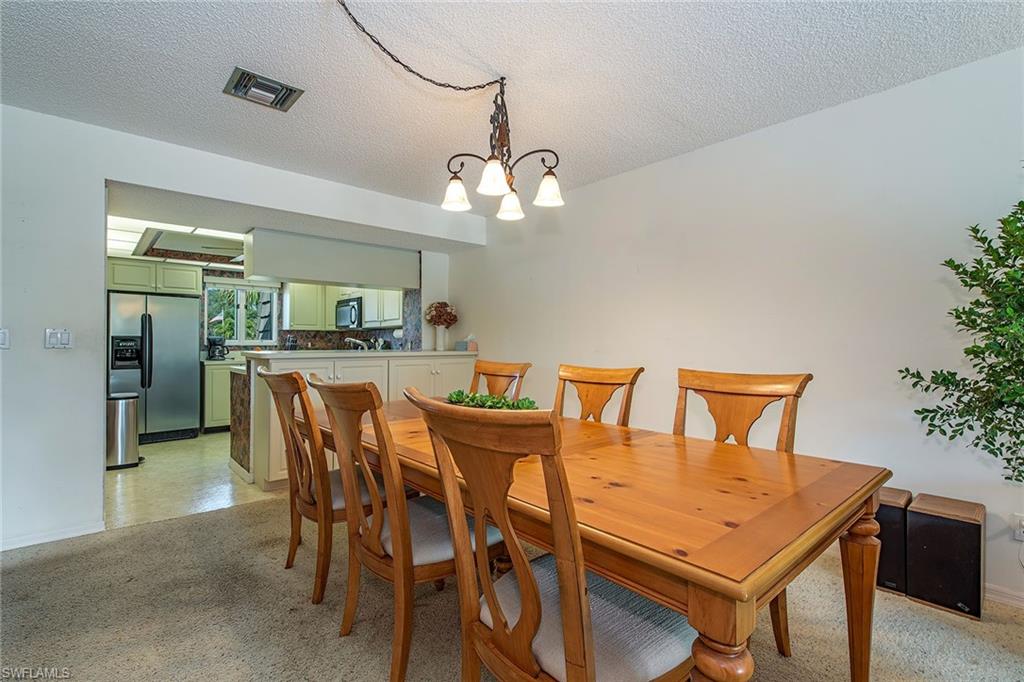 1672 Spoonbill Lane, Unit 1672 Naples, FL 34105 - Photo 5 of 12 a view of a dining room with furniture and chandelier