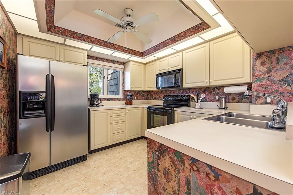 1672 Spoonbill Lane, Unit 1672 Naples, FL 34105 - Photo 6 of 12 a kitchen with stainless steel appliances granite countertop a refrigerator a sink a stove and white cabinets with wooden floor