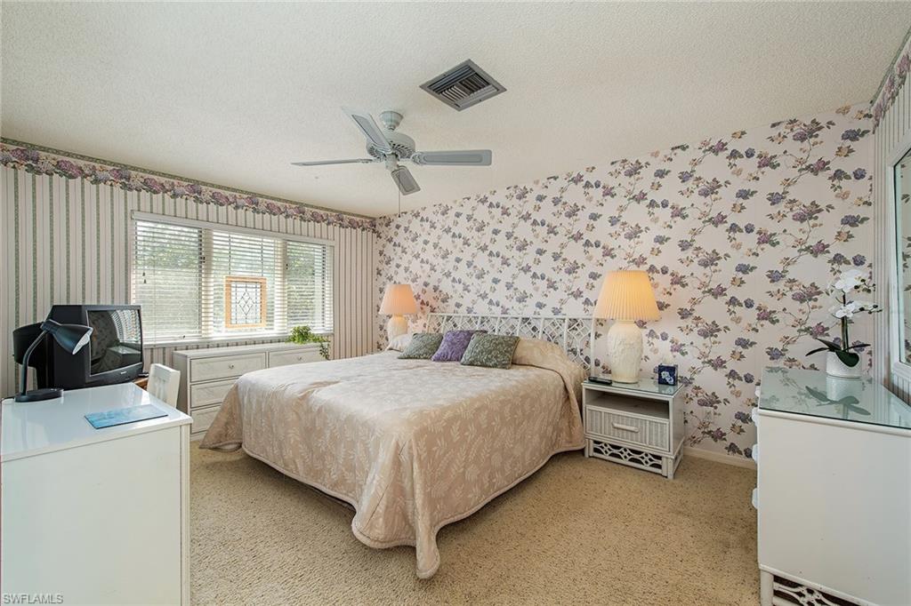 1672 Spoonbill Lane, Unit 1672 Naples, FL 34105 - Photo 8 of 12 a bedroom with a bed and dresser with mirror