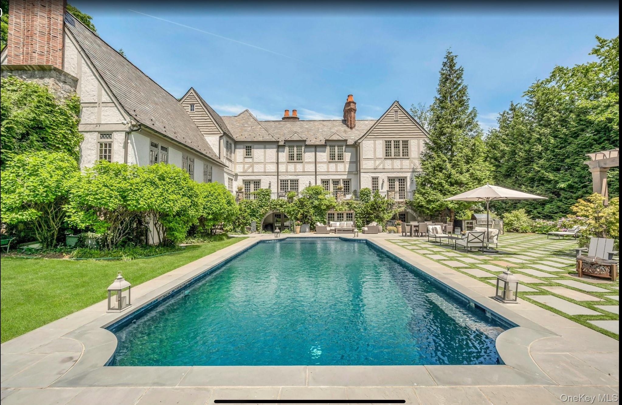 19 Park Drive South Rye, NY 10580 - Photo 3 of 42 This grand Tudor estate features a resort-caliber outdoor oasis centered around a sophisticated dark-bottom pool and a striking geometric stone terrace. The expansive grounds are masterfully designed for high-end entertaining, offering multiple al fresco lounges and dining zones within a lush, ultra-private perimeter.