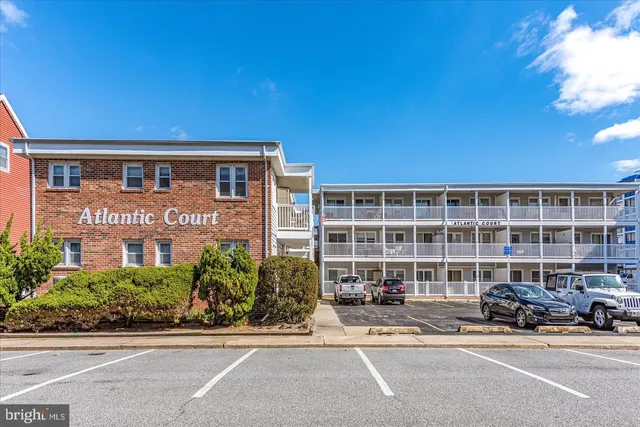 a front view of a building with a garden and parking space
