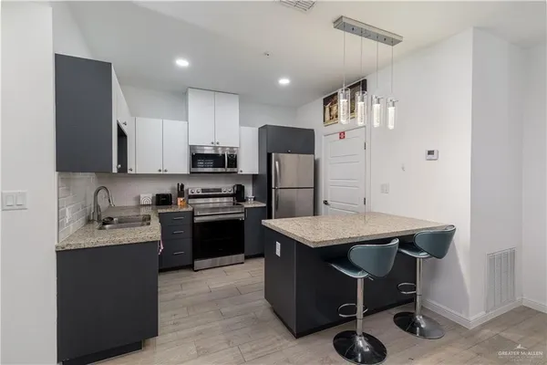 a kitchen with a refrigerator a stove top oven a sink and cabinets