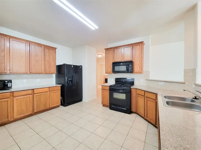 a kitchen with granite countertop a refrigerator stove top oven and sink