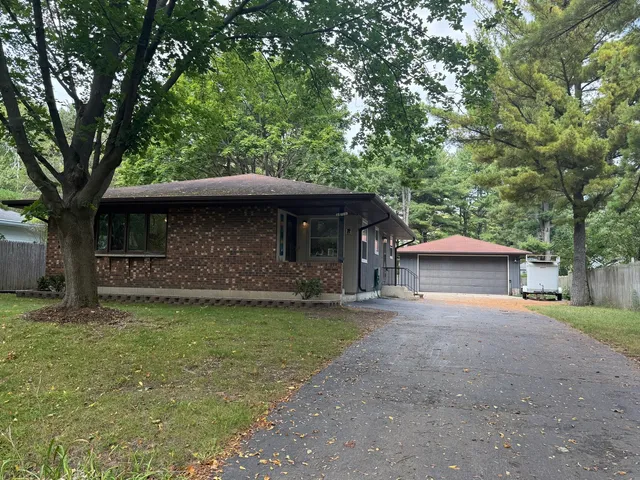 a front view of a house with a garden and trees