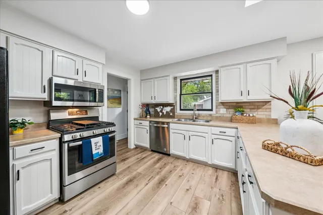 a kitchen with granite countertop a stove a sink dishwasher and a microwave oven with white cabinets