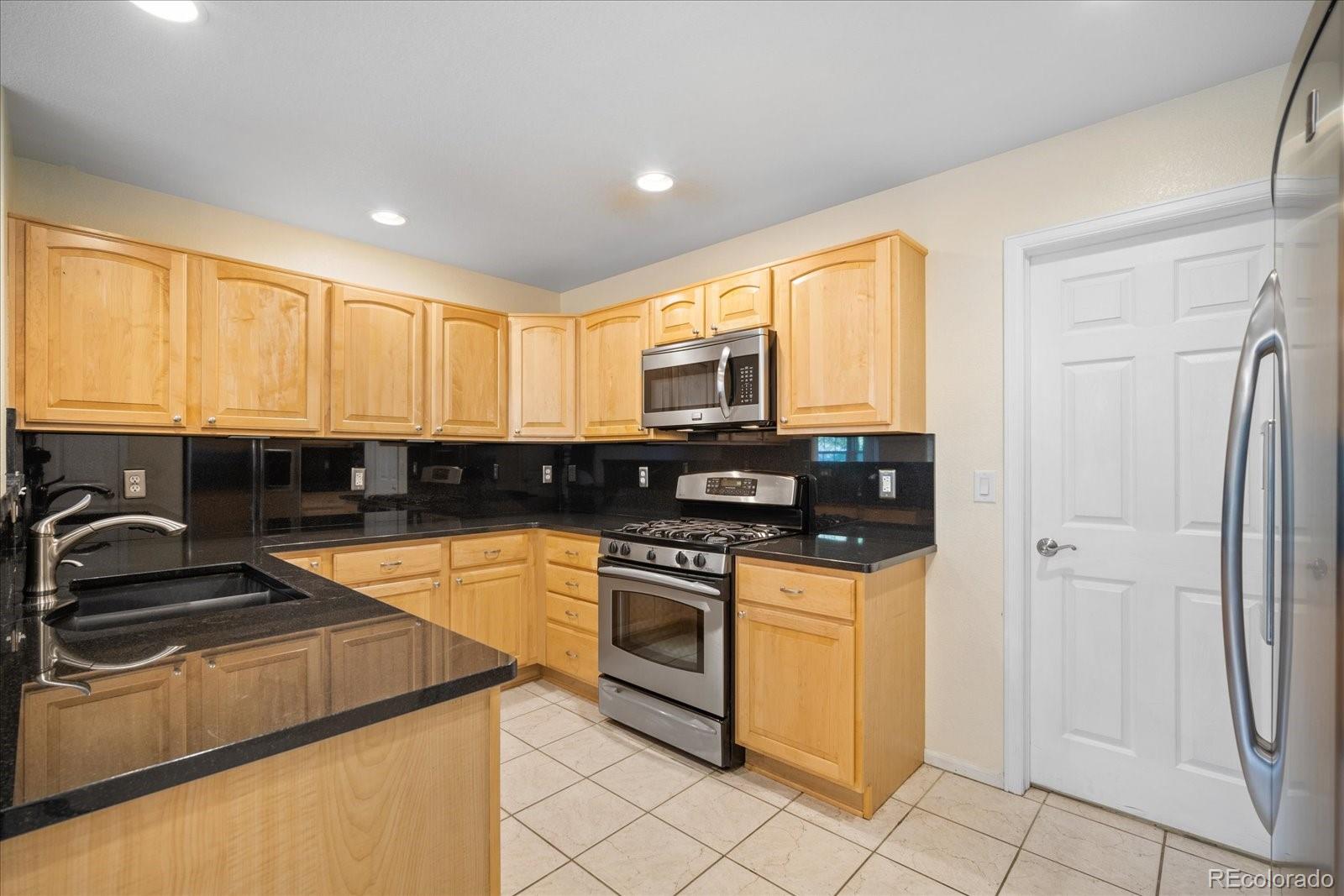 6115 Trailhead Road Highlands Ranch, CO 80130 - Photo 19 of 40 a kitchen with a sink a stove and cabinets