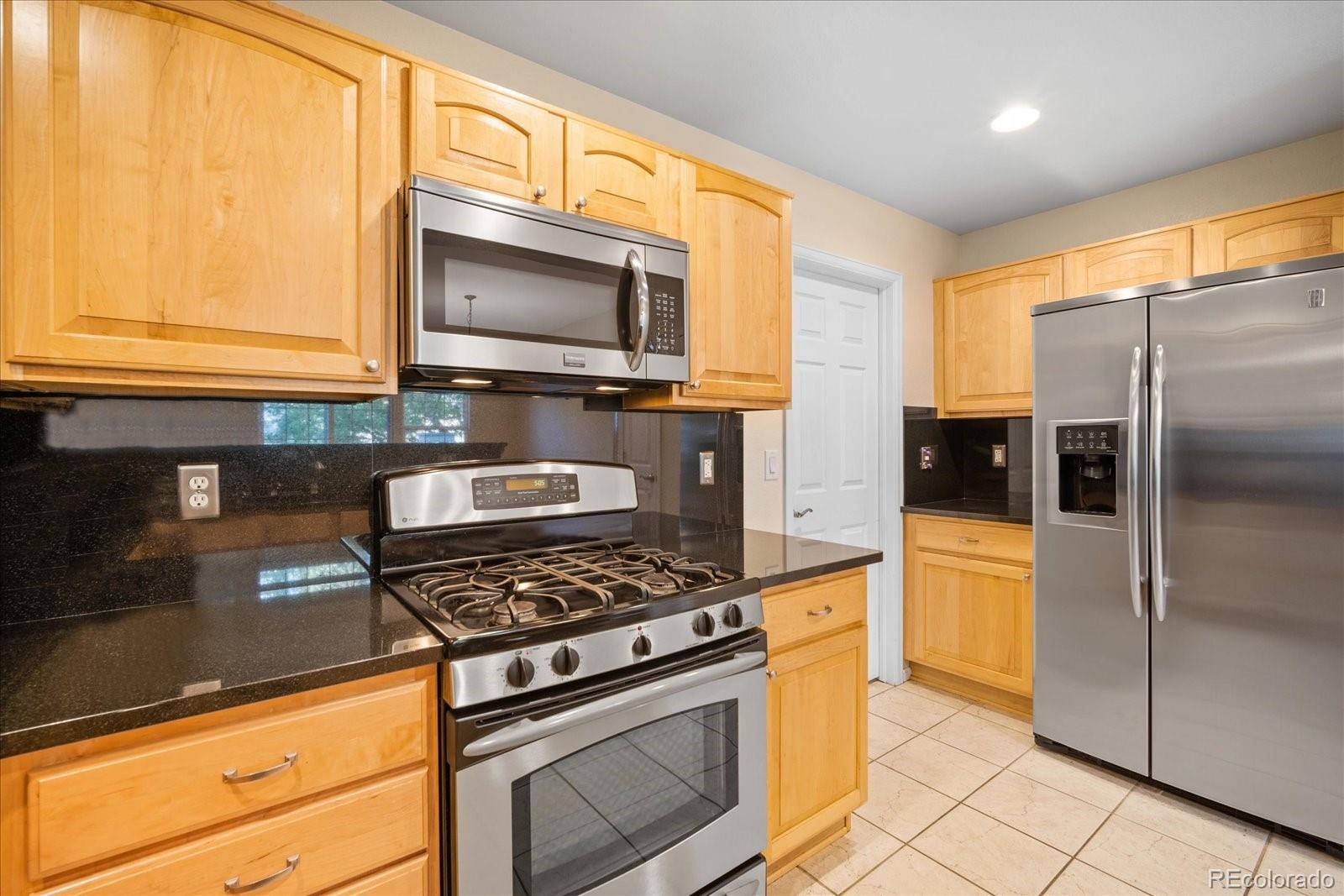 6115 Trailhead Road Highlands Ranch, CO 80130 - Photo 20 of 40 a kitchen with stainless steel appliances granite countertop a stove a sink and a microwave