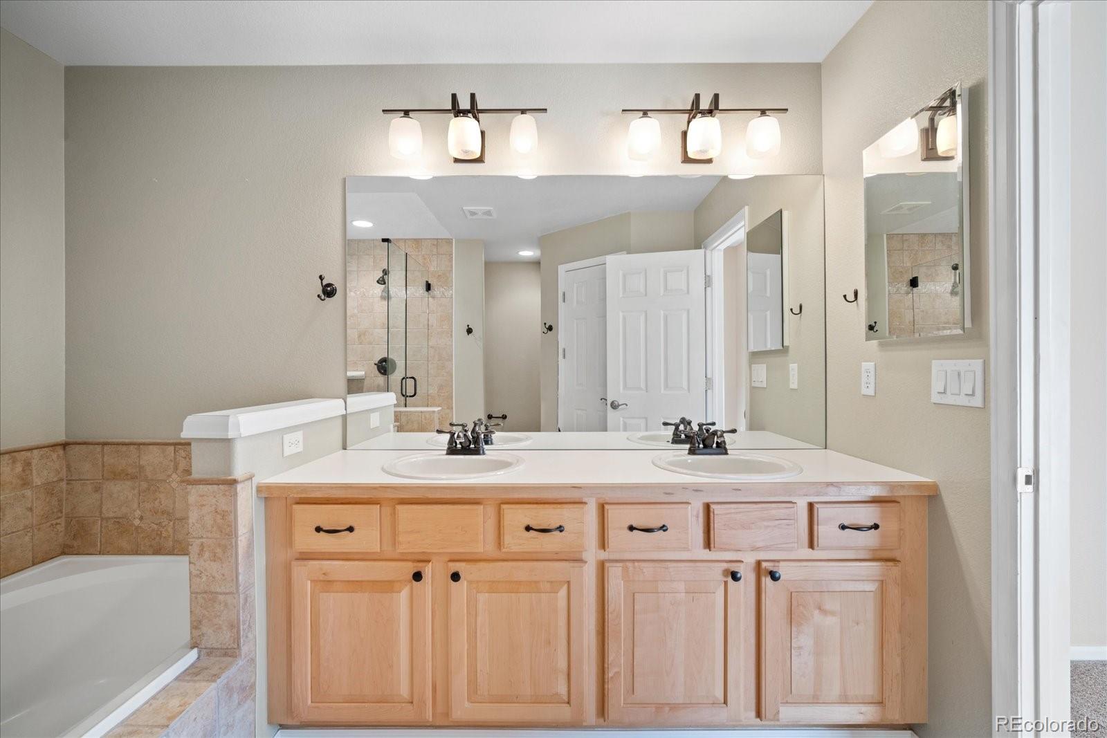 6115 Trailhead Road Highlands Ranch, CO 80130 - Photo 31 of 40 a bathroom with a sink vanity granite tub shower and a mirror