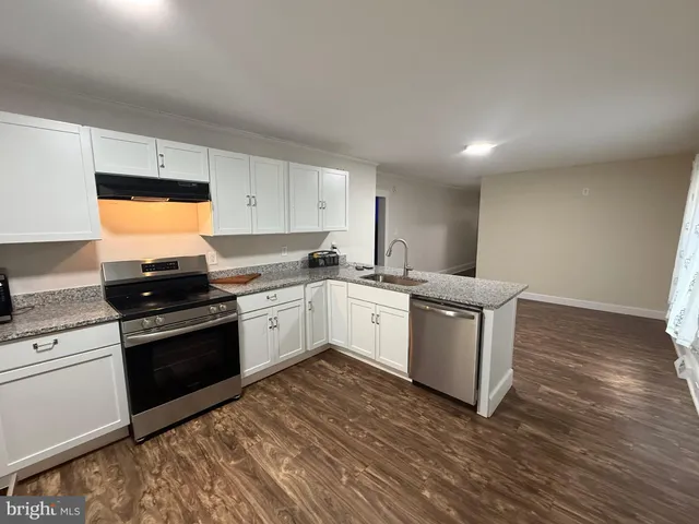 a white kitchen with wooden floor