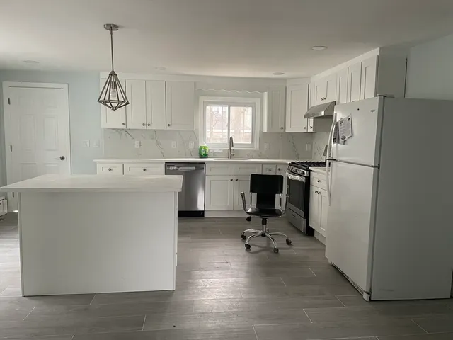a kitchen with a refrigerator a sink cabinets and a window