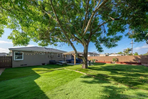 a view of a house with a big yard and large tree
