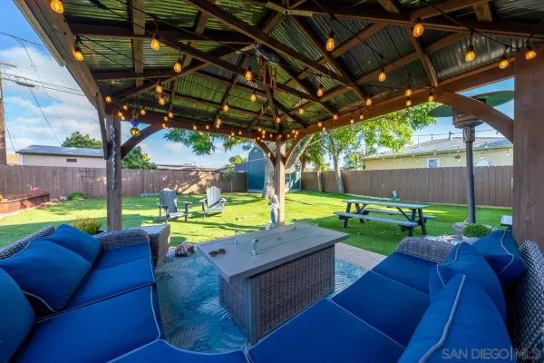 a view of a backyard with couches plants and large tree