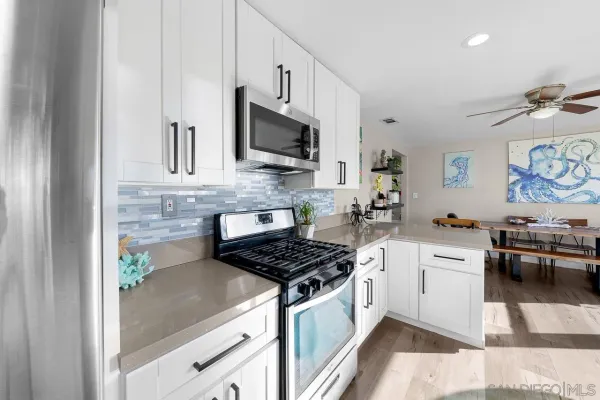 a kitchen with stainless steel appliances granite countertop white cabinets a stove top oven a sink and dishwasher