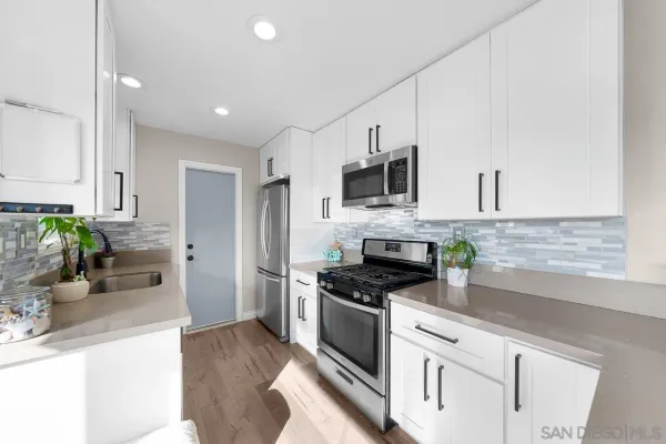 a kitchen with cabinets stainless steel appliances a sink and wooden floor