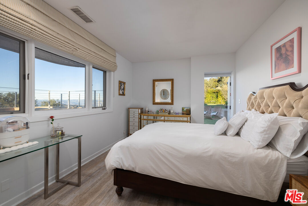 415 Stunt Road Calabasas, CA 91302 - Photo 27 of 38 a bedroom with a bed and wooden floor