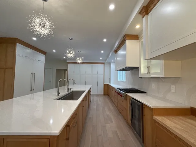 a large kitchen with stainless steel appliances kitchen island a large counter top and a wooden floors