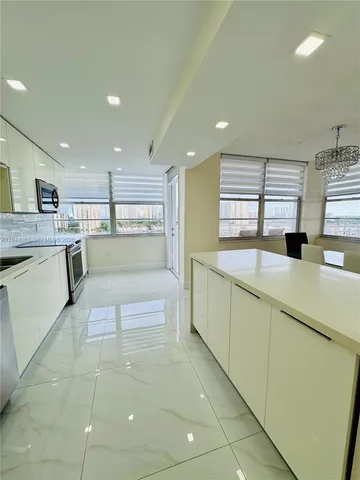 a large white kitchen with lots of counter space and a refrigerator