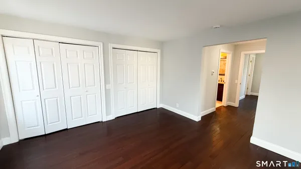 an empty room with wooden floor and windows with curtains view