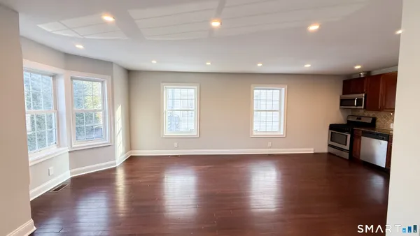 an open kitchen with granite countertop wooden floors stainless steel appliances a window and wooden floor