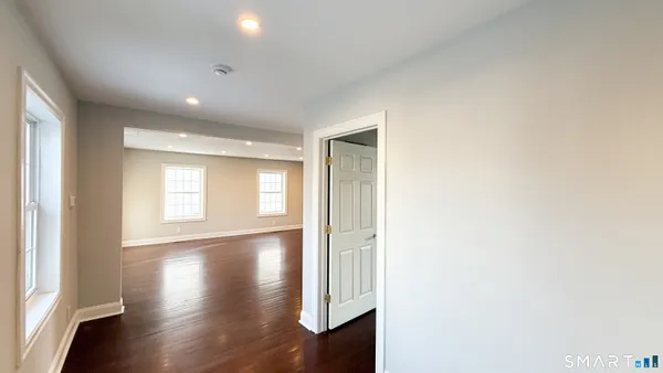 a view of empty room with wooden floor and fan