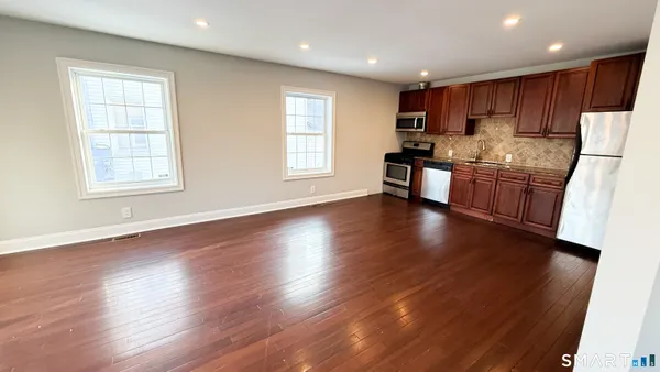 a kitchen with granite countertop wooden floors white cabinets and stainless steel appliances