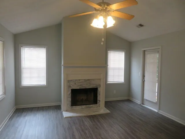an empty room with wooden floor a ceiling fan and a window