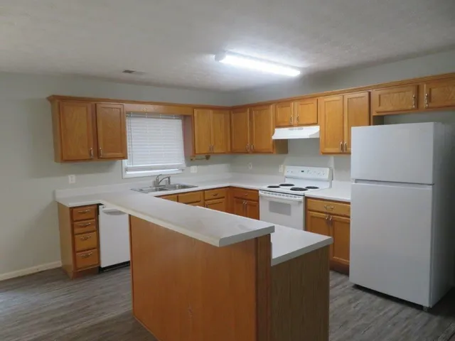 a kitchen with granite countertop a refrigerator stove and sink