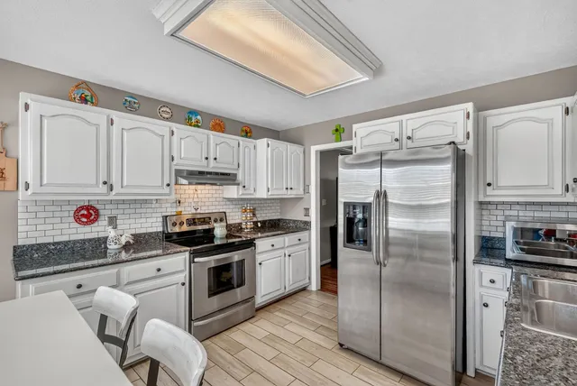a kitchen with white cabinets and stainless steel appliances