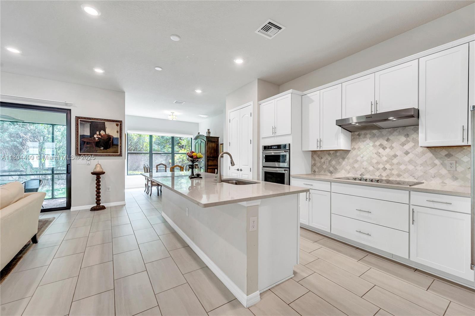 9206 Passiflora Way, Unit 101 Boca Raton, FL 33428 - Photo 24 of 60 a large kitchen with stainless steel appliances kitchen island granite countertop a refrigerator and a stove top oven