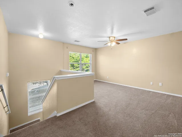 an empty room with windows and fan