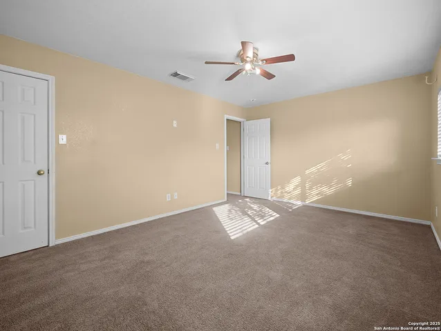 a view of an empty room with a chandelier fan