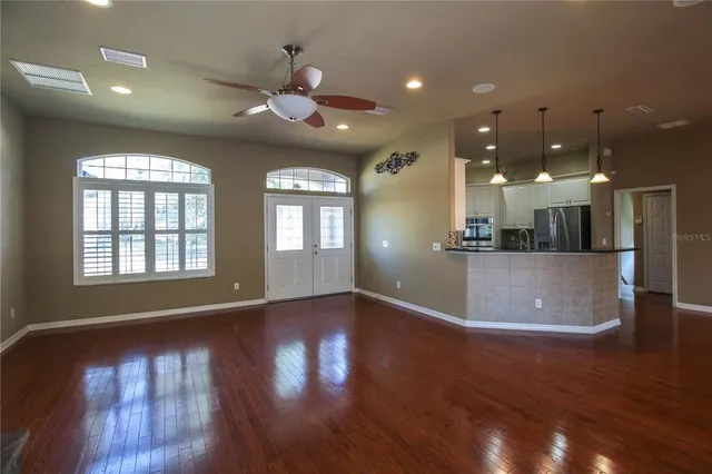 a view of a big room with wooden floor and windows