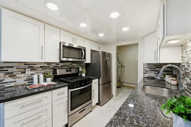 a kitchen with stainless steel appliances granite countertop a stove a sink and a refrigerator
