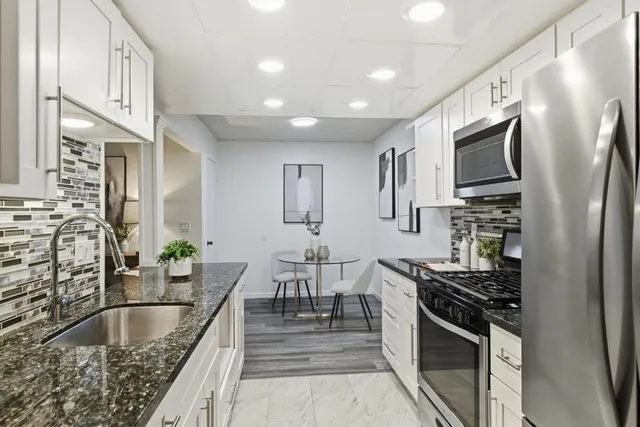 a kitchen with stainless steel appliances granite countertop a refrigerator and a stove top oven