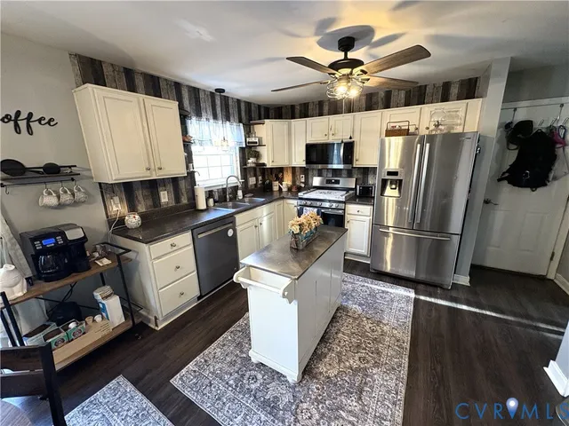 a kitchen with granite countertop a refrigerator a sink dishwasher stove top oven and cabinets