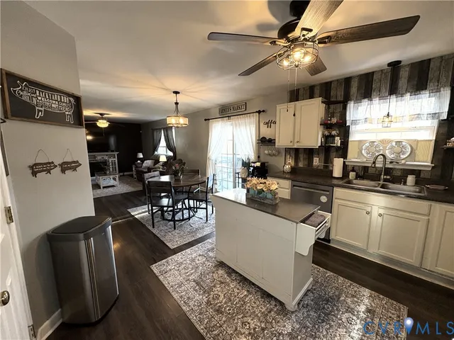 a kitchen with stainless steel appliances kitchen island granite countertop a refrigerator a stove a sink dishwasher and white cabinets with wooden floor