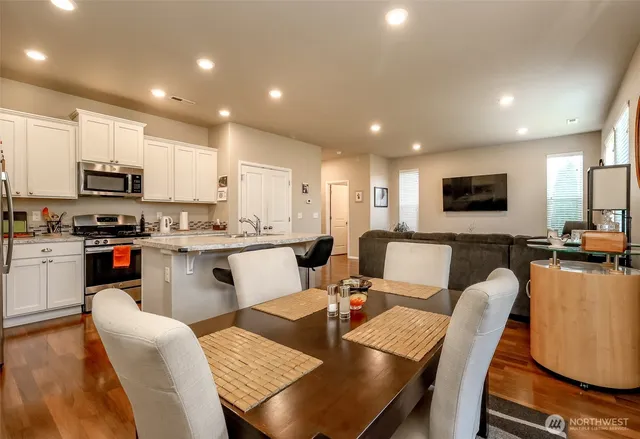 a kitchen with stainless steel appliances granite countertop a stove a table and chairs