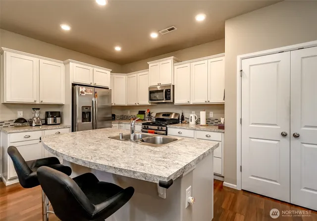 a kitchen with stainless steel appliances granite countertop a stove refrigerator sink and cabinets