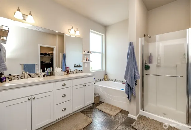 a bathroom with a double vanity sink a mirror a bathtub and shower