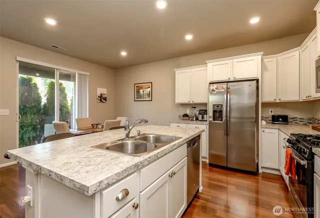 a kitchen with stainless steel appliances granite countertop a sink and a refrigerator