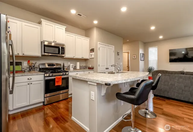 a kitchen with stainless steel appliances granite countertop a stove a sink a microwave a refrigerator and cabinets