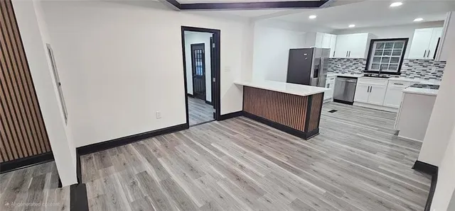 a view of kitchen with stainless steel appliances kitchen island wooden floor and refrigerator
