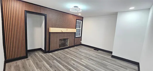 a view of an empty room with wooden floor and a fireplace
