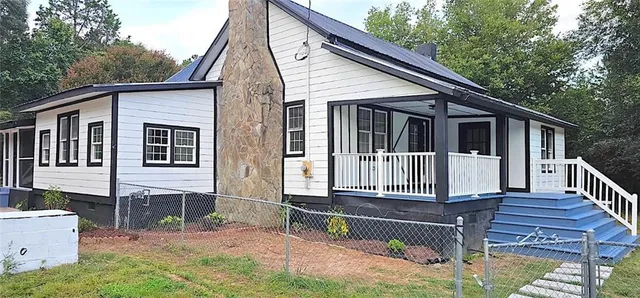 a view of house with wooden deck and a yard