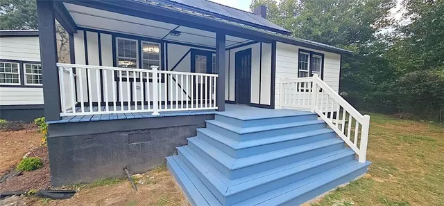 a view of a house with wooden deck and furniture